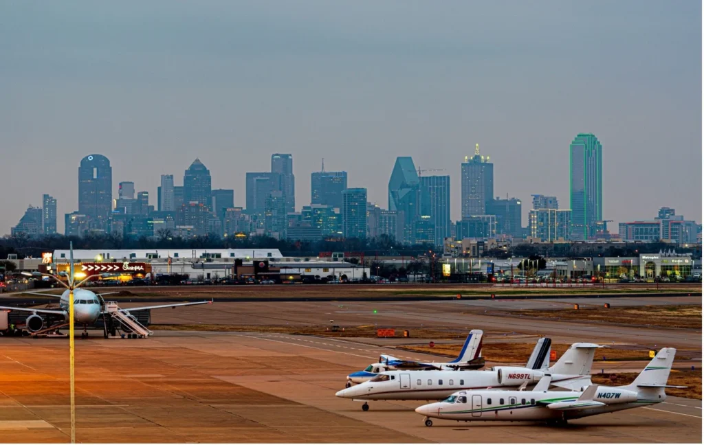 Airport apron with aircraft and city skyline under cloudy weather conditions