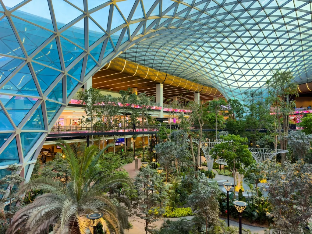 Modern airport terminal with glass roof, indoor greenery and passenger areas