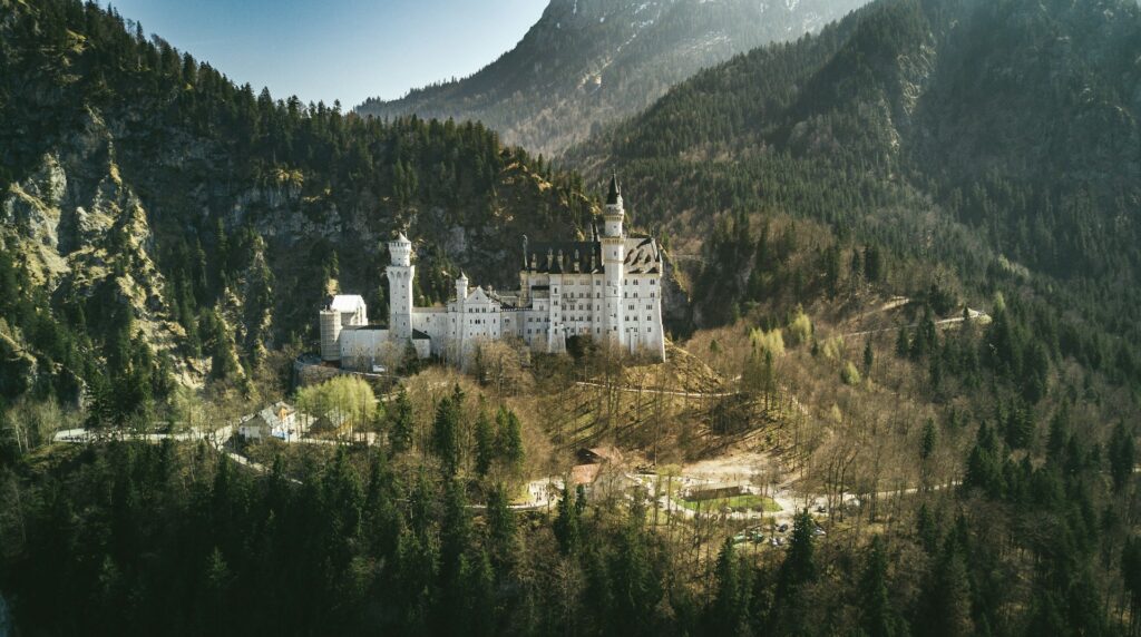 Schloss Neuschwanstein in Bayern mit Bergen bei einem Rundflug